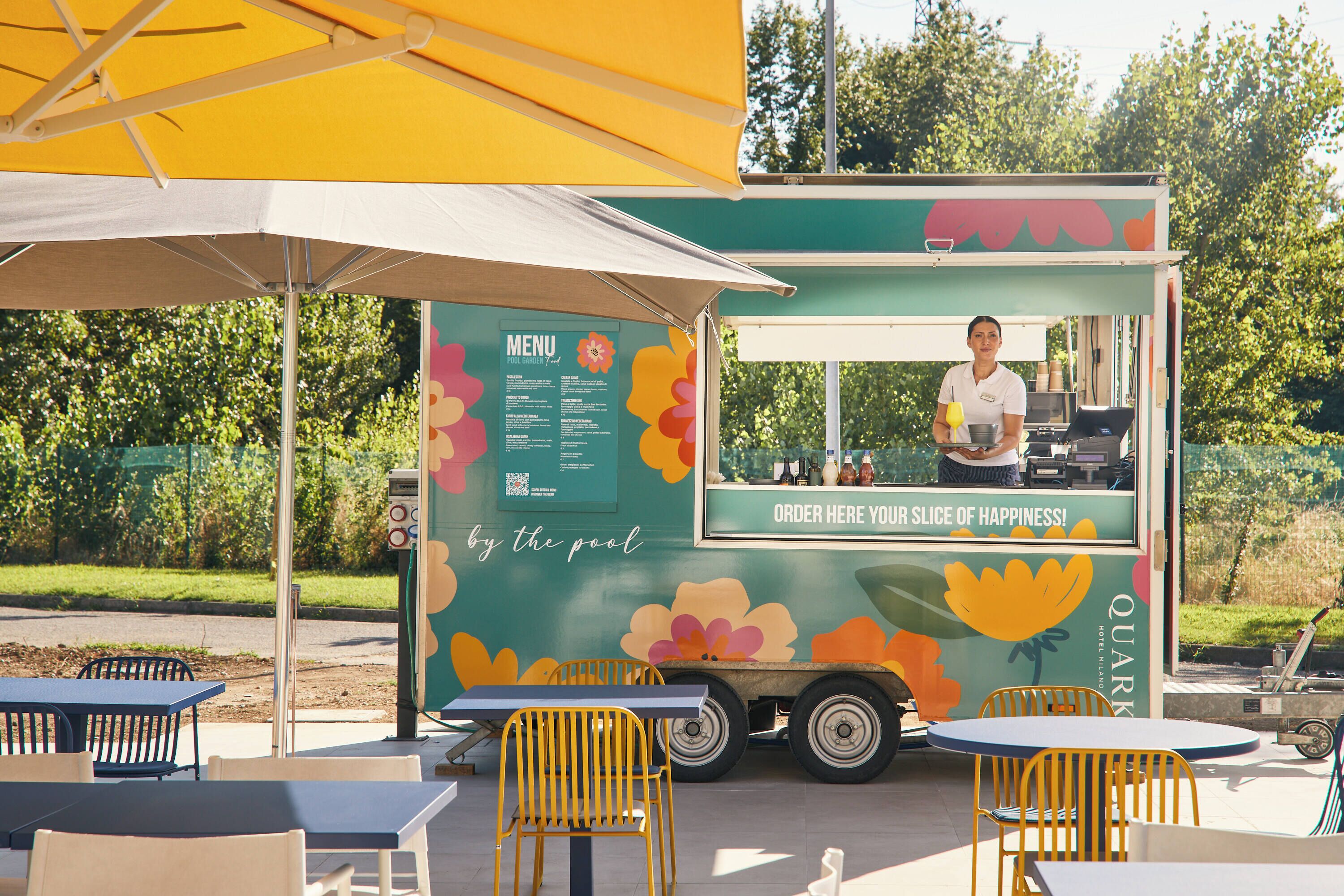 Un food truck con un menù e un cartello che dice 'ORDER HERE YOUR SLICE OF HAPPINESS!'.