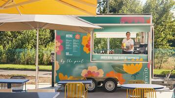 Un food truck con un menù e un cartello che dice 'ORDER HERE YOUR SLICE OF HAPPINESS!'.