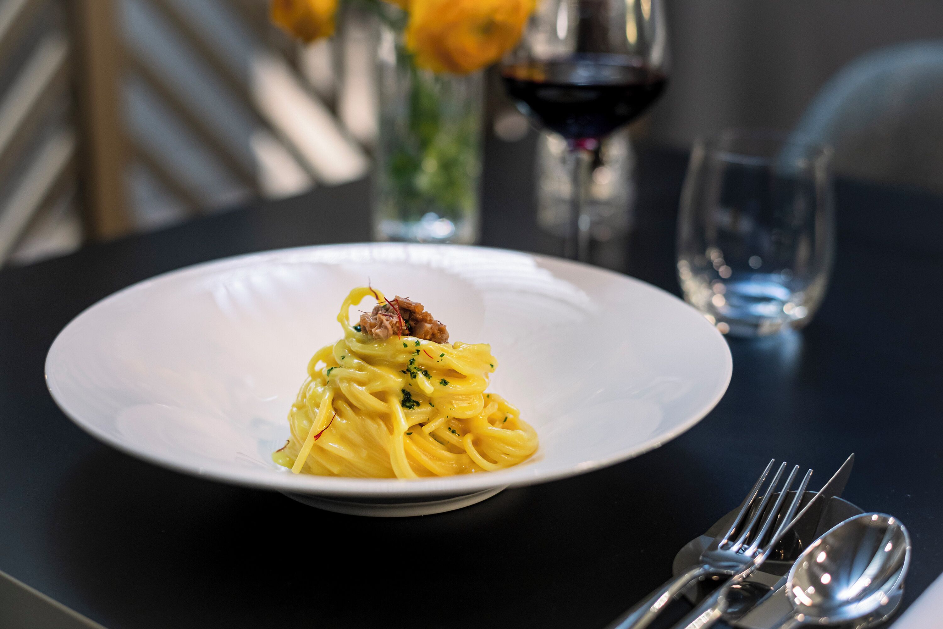 A plate of pasta with a fork and spoon on a table.