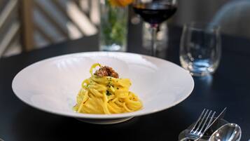 A plate of pasta with a fork and spoon on a table.