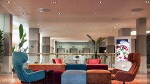 A modern lobby with colorful seating, a large digital pizza advertisement, and a view of the interior through a glass railing. - Quark Hotel Milano (Milan)