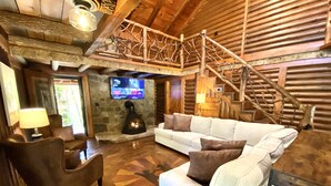 A cozy living room with a stone fireplace, a white sofa, and a brown leather armchair.