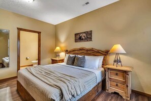 A bedroom with a wooden bed, two bedside tables with lamps, a door, and a wall-mounted picture.