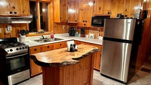 A kitchen with wooden cabinets, a stainless steel refrigerator, a gas stove, and a microwave. - Cozy Errol Home conveniently close to town and with snowmobile access!  (Errol)