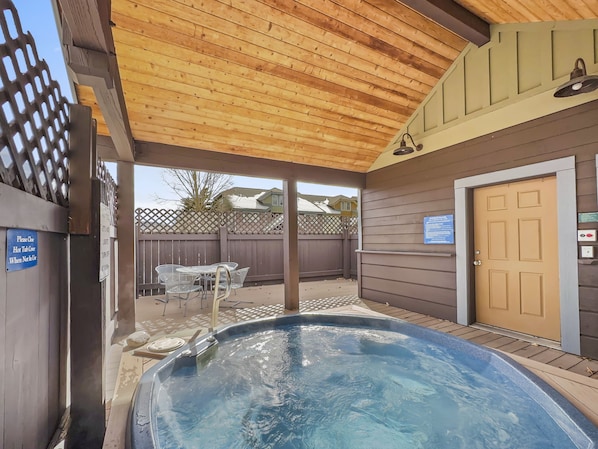 A hot tub area with a wooden ceiling, a door, and a fenced patio.