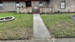 Un edificio de ladrillo con techo rojo, un letrero de bienvenida y una fuente circular para pájaros.