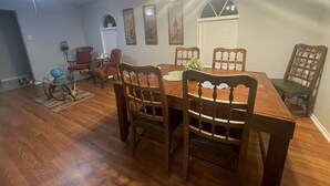 Un comedor con una mesa y sillas de madera, ventilador de techo e iluminación en la pared.