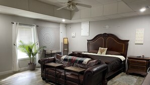 Een slaapkamer met een groot bed, een leren bank, een bijzettafeltje en een nachtkastje.