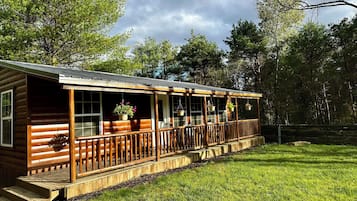 Situated in a serene setting, this cabin offers a covered deck and a spacious porch with multiple windows.