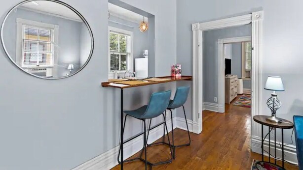 Une cuisine moderne avec un coin bar, un plancher en bois et un miroir au mur.