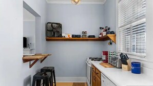 Une cuisine de taille réduite, équipée d’une cuisinière à gaz, de meubles blancs et d’un plan de travail en bois.