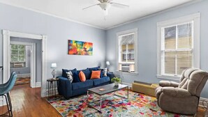 Un salon avec un canapé bleu, une table basse, un fauteuil beige et un tapis coloré.