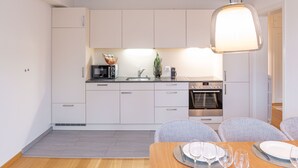Een moderne keuken met witte kastjes, een magnetron, een fornuis en een eethoek met een tafel gedekt voor vier personen.