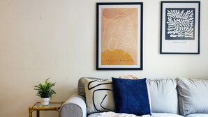 A living room with a grey sofa, a small side table with a plant, and two framed artworks on the wall. - Pink Sunshine beach apartment (Torrevieja)