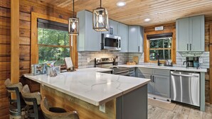 Een moderne keuken met houten kastjes, een groot eiland en hanglampen.