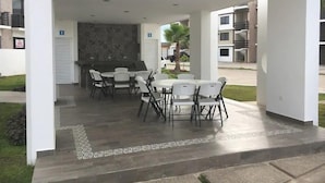 An outdoor patio with a dining area, a grill, and a patterned wall. - Departamentos Pacific Blue (Mazatlán)