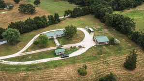 An aerial view of a rural property with a main house, a smaller structure, and a barn. There are several trees and a winding driveway. - Sunset Ridge perfect vacation home near Meramec River (Leasburg)