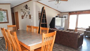 A spacious living room with a wooden dining table and chairs, a large TV, and a sofa. - Sunset Ridge perfect vacation home near Meramec River (Leasburg)