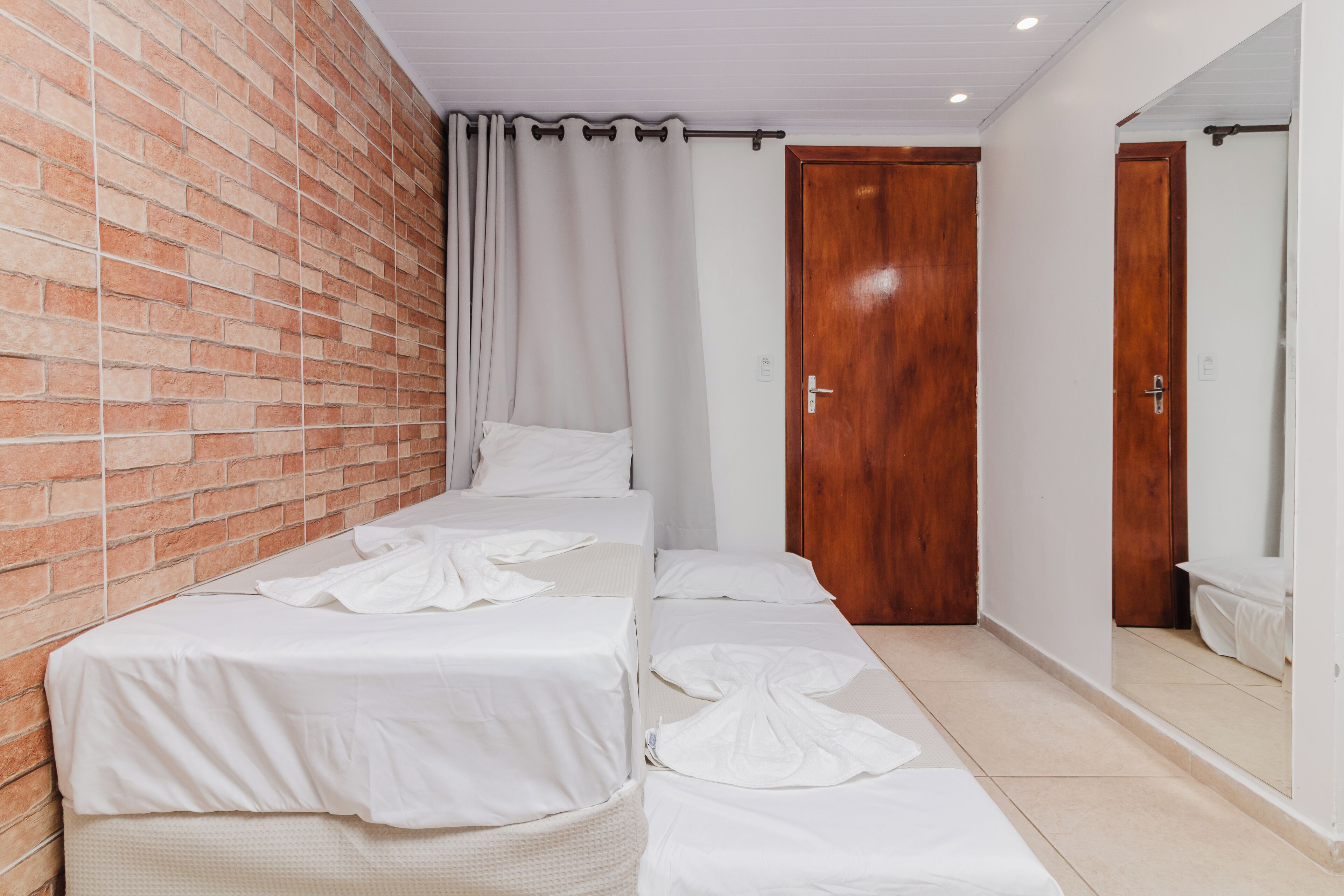 A hotel room with a brick wall, a wooden door, and a large mirror.