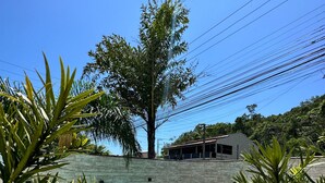 A swimming pool with a stone wall and a building in the background. - Ancoradouro Pousada (Penha)