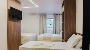 A hotel room with two beds, a TV mounted on the wall, and a window with curtains. - Ancoradouro Pousada (Penha)