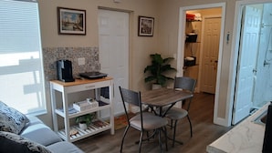 Ein gemütlicher Wohnraum mit Esstisch, Stühlen, einer Kaffeestation, einer Couch und einer Küchenzeile.