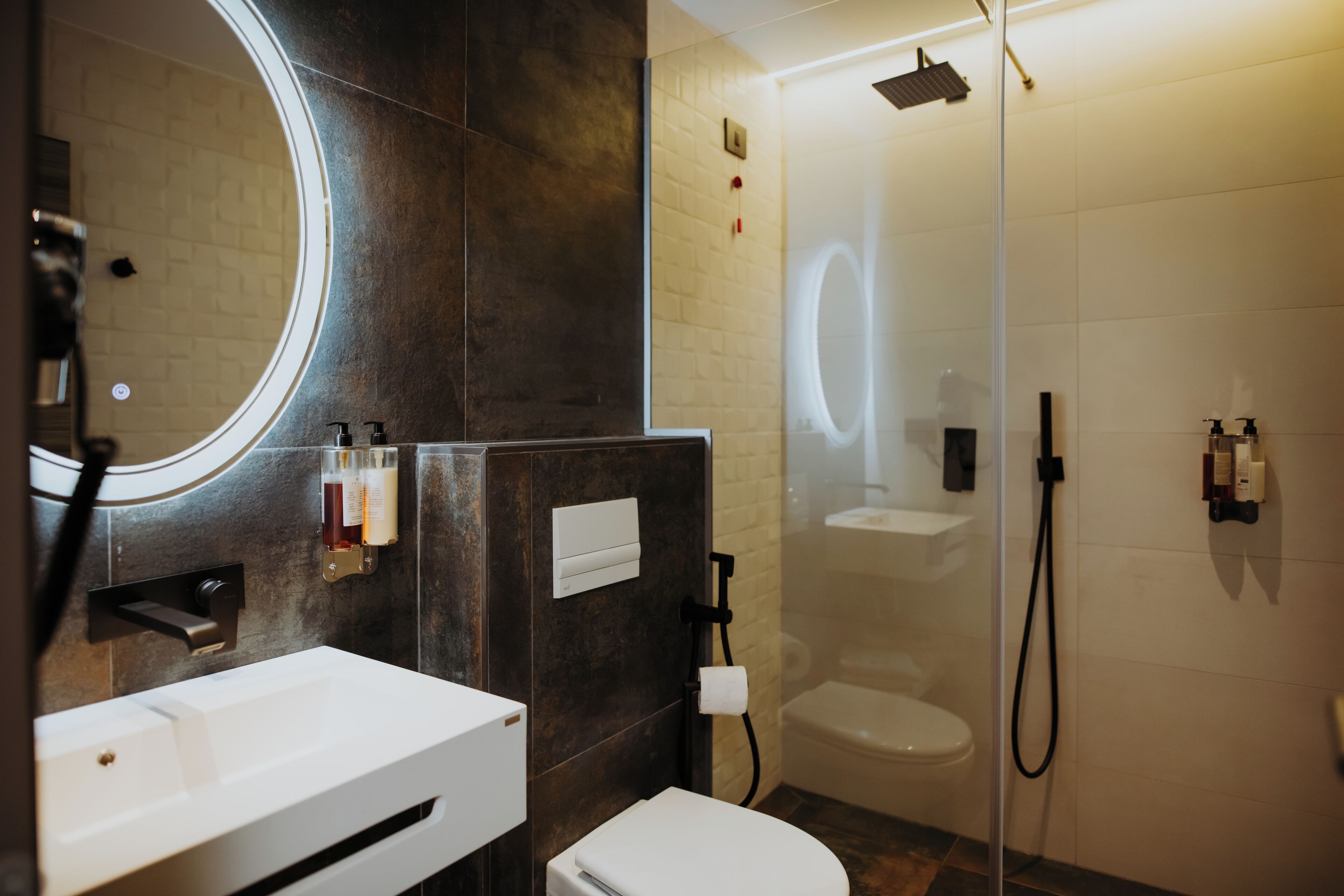 Un baño moderno con un lavabo blanco, un inodoro y una zona de ducha con mampara de vidrio.