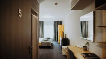 A hotel room with a bed, a desk, a chair, a television, and a window with curtains.