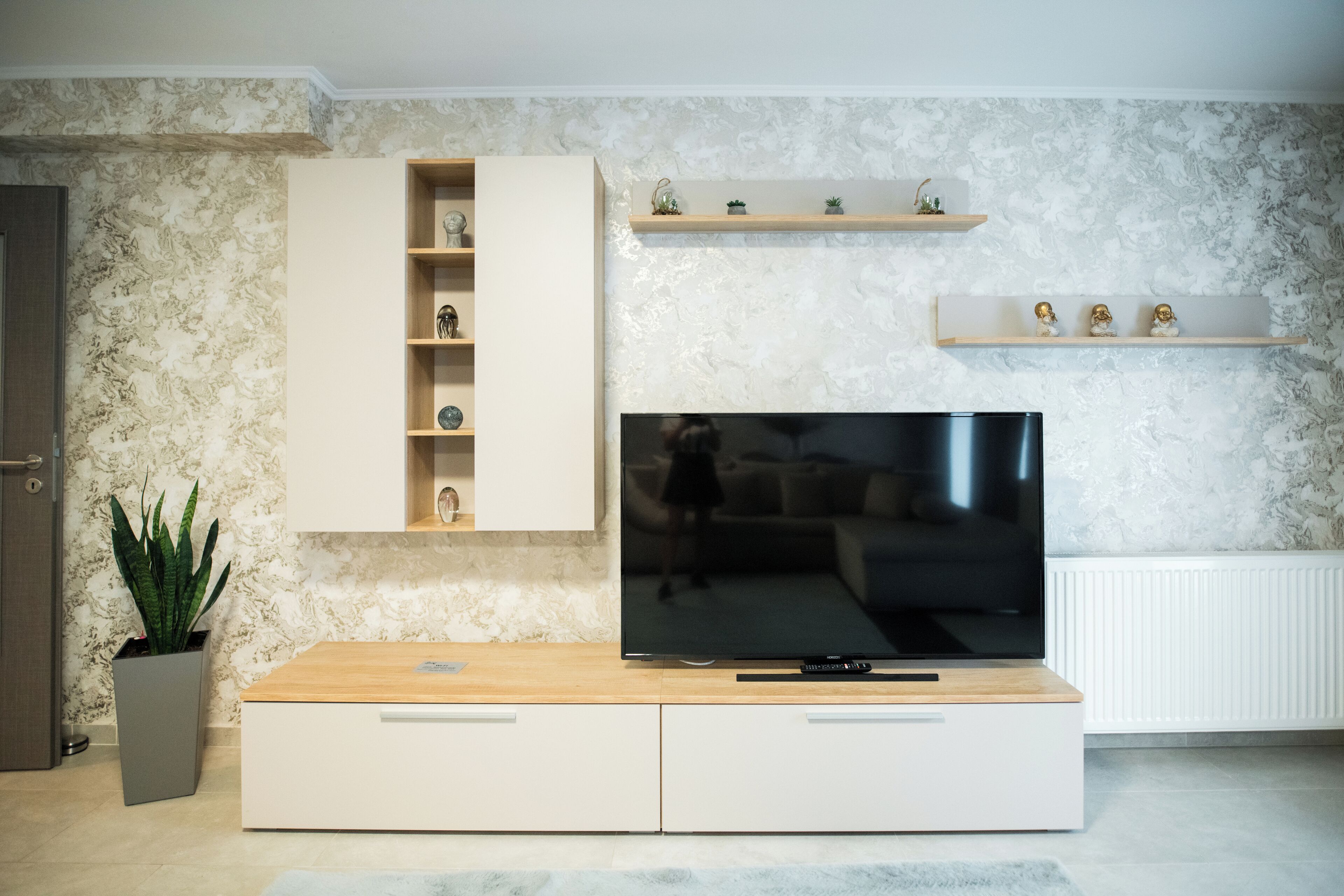 A modern living room with a flat-screen TV, built-in shelving, and decorative items.