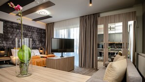Una sala moderna con una mesa de centro de madera, un sofá, un televisor y un comedor con una mesa y sillas.