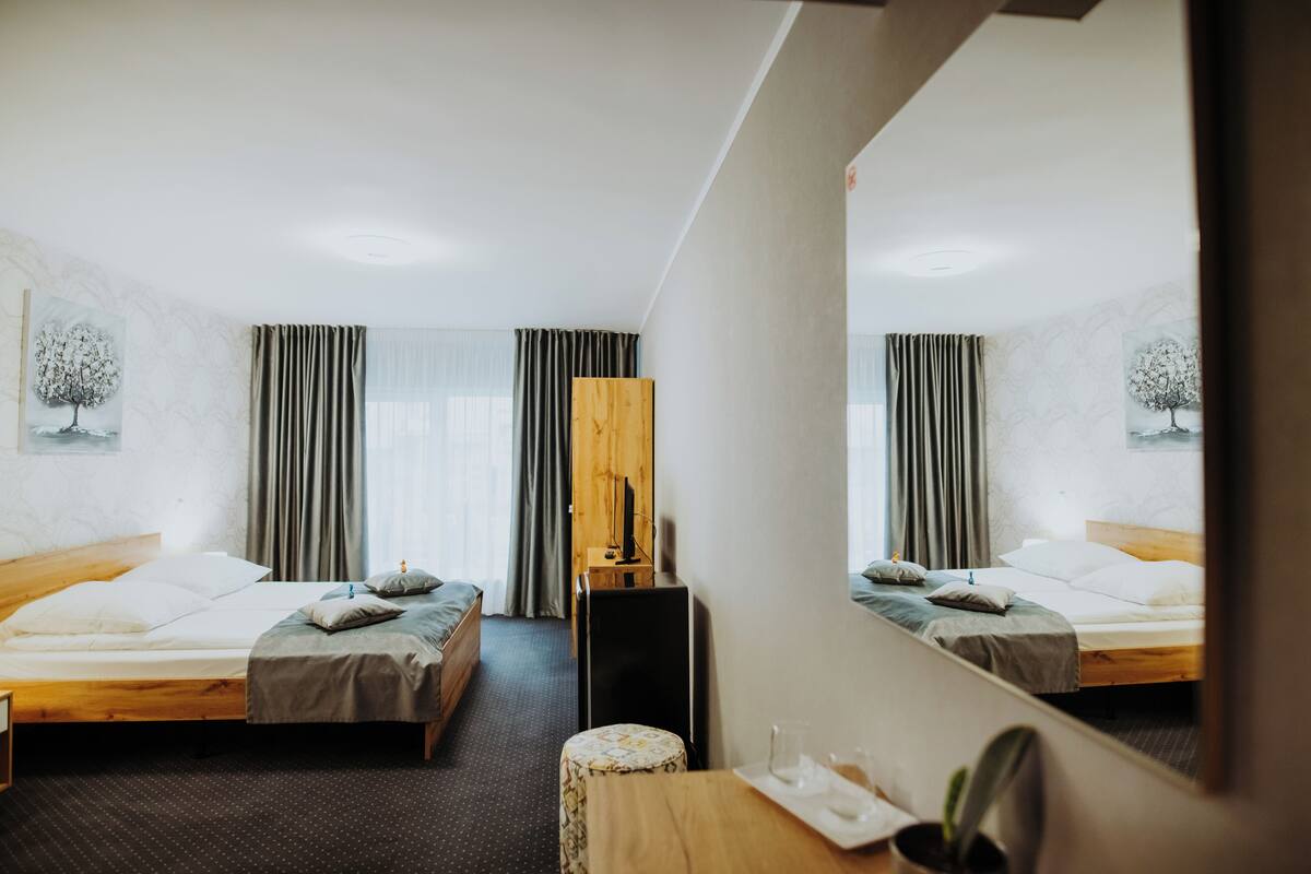 A hotel room with two beds, a wooden dresser, a small table, and a mirror.