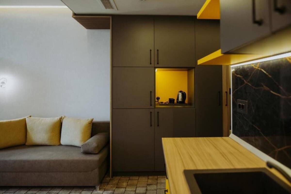 A compact living space with a sofa, a kitchenette with cabinets, and a countertop.
