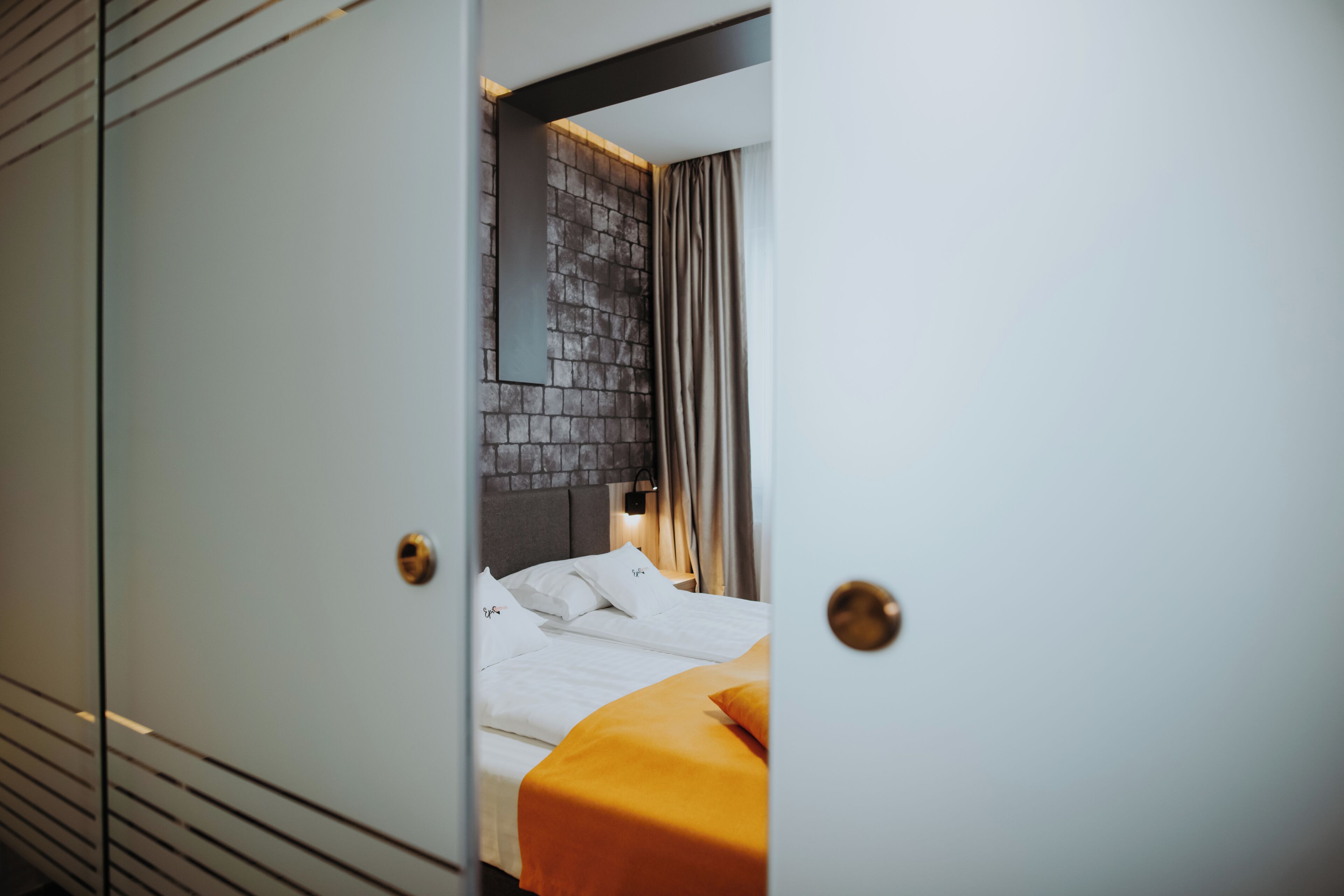 A hotel room with a bed, a headboard, and a curtain.