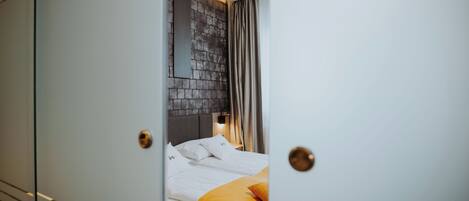 A hotel room with a bed, a headboard, and a curtain.