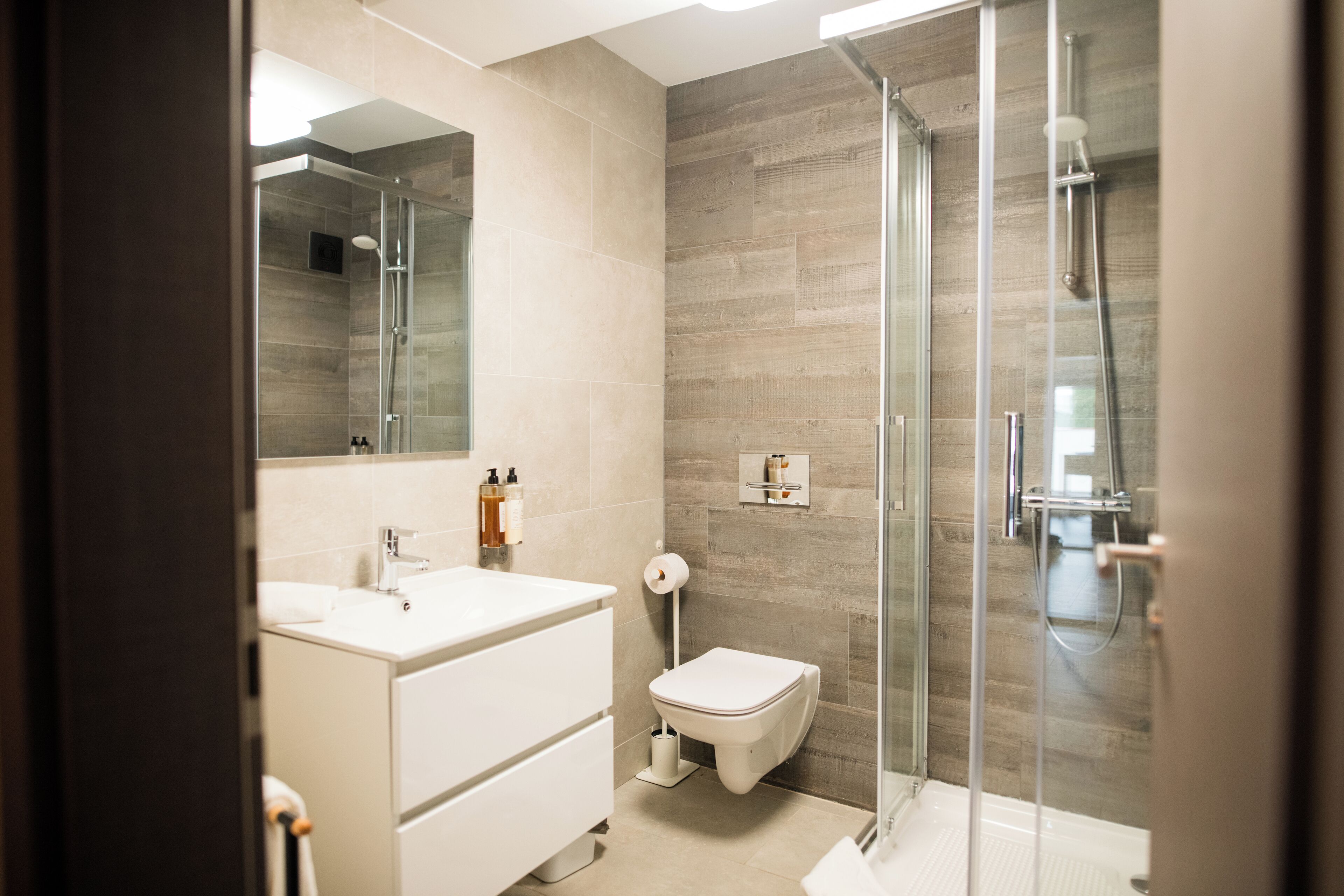 A modern bathroom with a glass shower enclosure, a white sink, and a toilet.