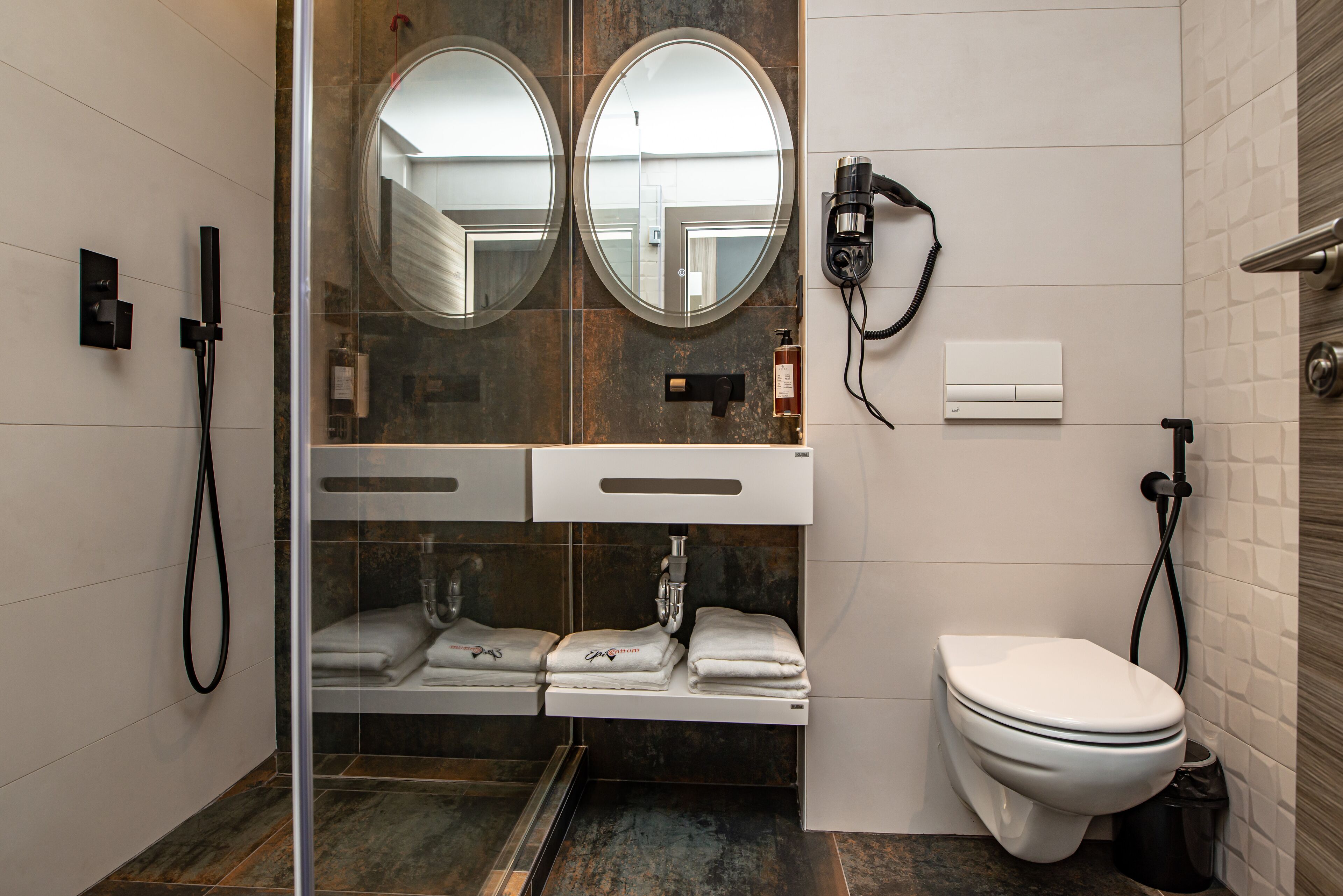 A modern bathroom with a glass-enclosed shower, a white toilet, and a hairdryer mounted on the wall.