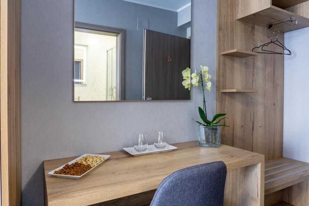 Een moderne badkamer met een houten wastafelmeubel, een spiegel, een kleine plant en een schaal met lekkernijen.