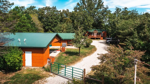 Een lodge met een onverhard pad dat leidt naar een houten hut en een groter gebouw met een veranda.