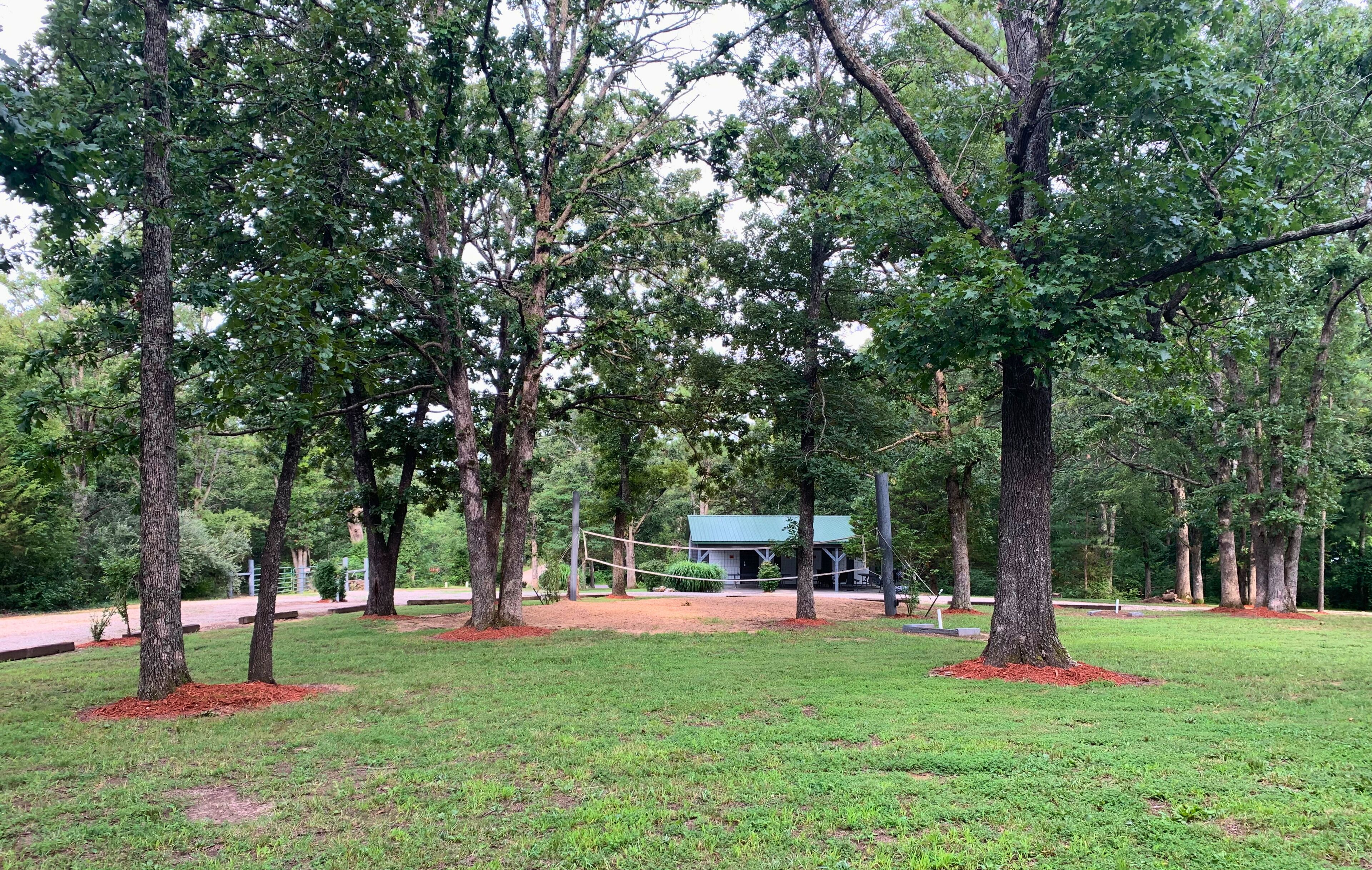 A park with trees, a playground, and a small building.