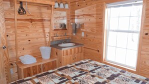 A wooden cabin room with a bed, a sink, and a window. - Fletcher's Village Group Cabin rental near Meramec River. (Leasburg)