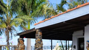 A covered patio area with stone pillars, potted plants, and a pool in the background. - Casa Cateyma with pool (Icod de los Vinos)