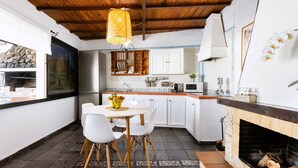 A compact kitchen with white cabinets, a stone countertop, and a fireplace. - Casa Cateyma with pool (Icod de los Vinos)