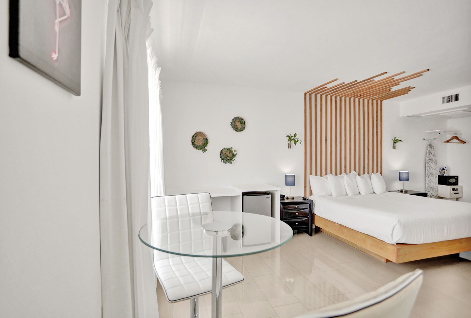 Ein modernes Hotelzimmer mit einem Bett, einem Glastisch, einem Sessel, einem Schreibtisch und einem Kleiderschrank.