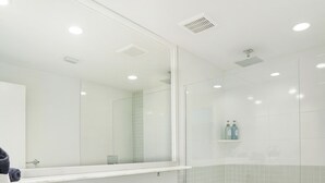 Une salle de bain moderne avec un lavabo rond, des toilettes et une douche à parois de verre.