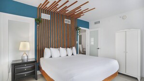 Une chambre avec un grand lit, une table de chevet avec des tiroirs, une plante fixée au mur et une armoire.