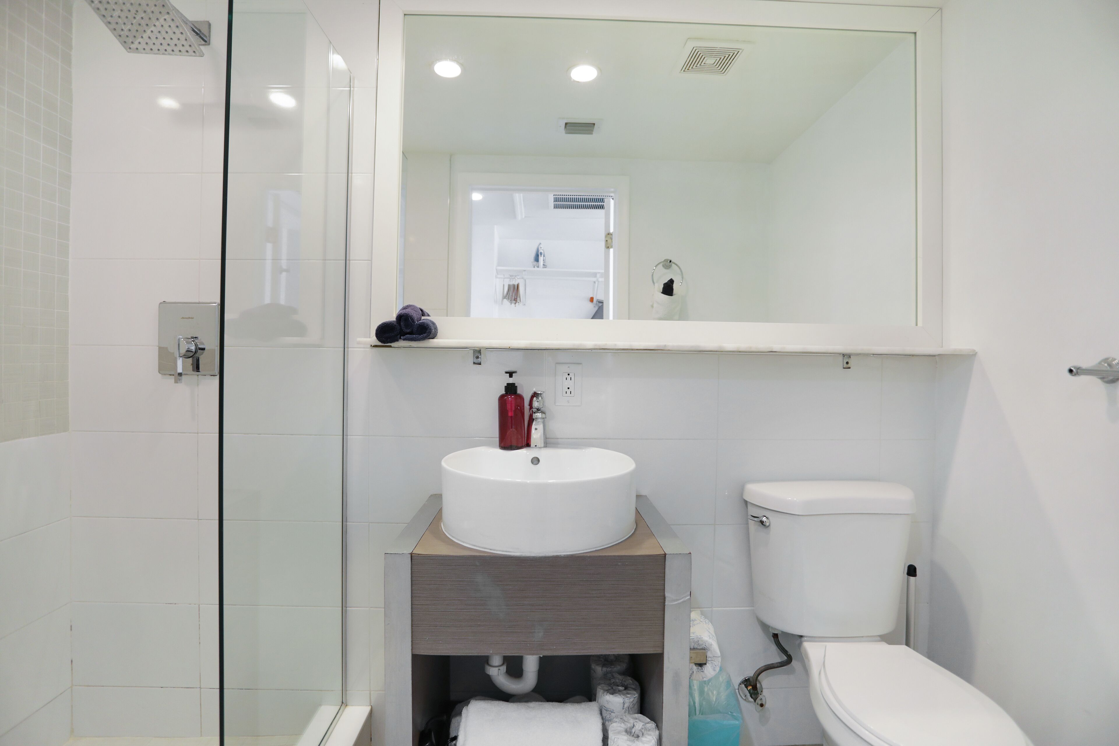 A modern bathroom with a glass shower enclosure, a white sink with a mirror above it, and a toilet.