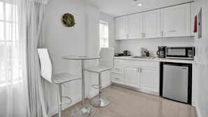 A modern kitchen with white cabinets, a stainless steel refrigerator, a microwave, and a small dining area with two bar stools. - NEW LISTING! Premium 2 bedroom/2bathroom Sleeps 7 (Miami)