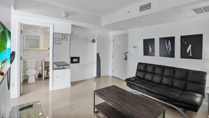 A modern living room with a black leather sofa, a wooden coffee table, and a painting on the wall. - NEW LISTING! Premium 2 bedroom/2bathroom Sleeps 7 (Miami)