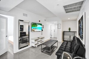 Ein modernes Wohnzimmer mit einer schwarzen Ledersofa, einem Couchtisch und einem Fernseher an der Wand.