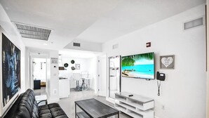Een moderne woonkamer met een leren bank in het zwart, een salontafel, een flatscreen televisie en een minimalistisch ontwerp.